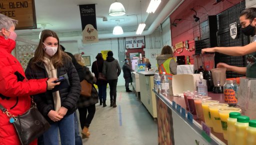 A young customer selecting a smoothie from a fresh juice vendor at the Fredericton Boyce Farmers Market