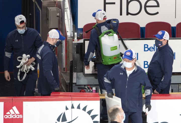 Arena workers clean the player's bench before NHL hockey action between the Edmonton Oilers and Montreal Canadiens, in Montreal, Thursday, Feb. 11, 2021. The game has been delayed by an hour after an Oilers player was placed on the league's COVID-19 protocol. 