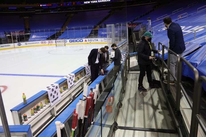 Due to updated COVID-19 protocols, the glass has been removed from behind the team benches as workers take measurements for additional safety methods prior to an NHL hockey game between the Washington Capitals and the New York Rangers at Madison Square Garden on Thursday, Feb. 4, 2021, in New York. 