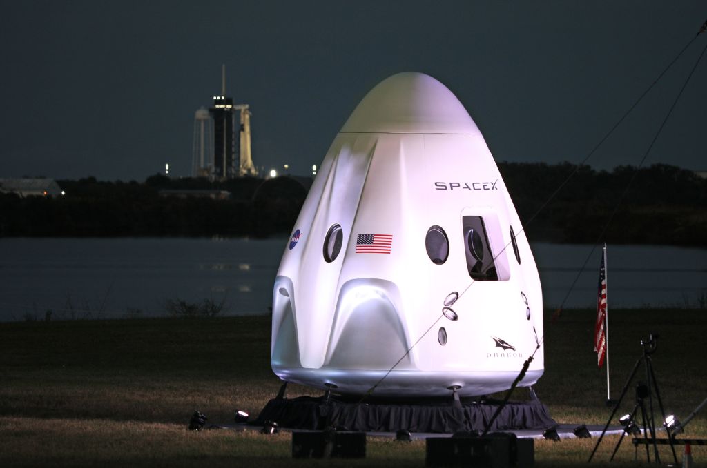 A full-size model of the Crew-1 spacecraft module sits near the launch pad as a SpaceX Falcon 9 rocket is seen at launch complex 39A in the distance at the Kennedy Space Center in Florida on Nov. 15, 2020.