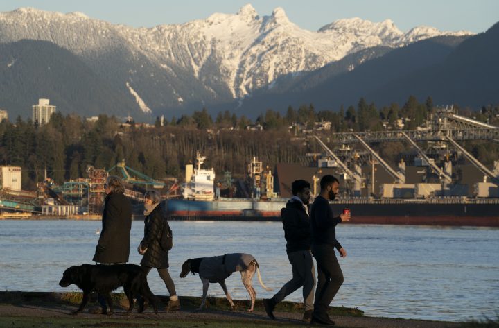 The North Shore mountains are pictured in the background as people walk along the waterfront in Vancouver, Monday, Jan. 18, 2021.  