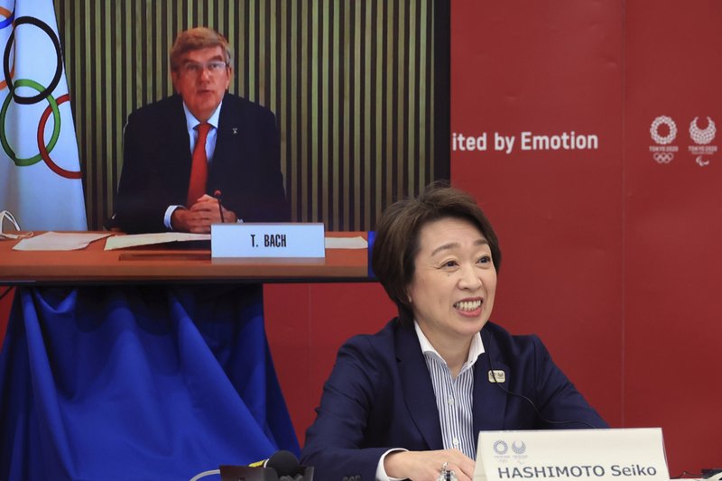 International Olympic Committee (IOC) President Thomas Bach, on a screen, delivers an opening speech while Tokyo 2020 Organizing Committee President Seiko Hashimoto listens at a five-party meeting of Tokyo 2020 Olympic and Paralympic Games with International Paralympic Committee (IPC) President Andrew Parsons, Tokyo Gov. Yuriko Koike and Japanese Olympic Minister Tamayo Marukawa in Tokyo Saturday, March 20, 2021.