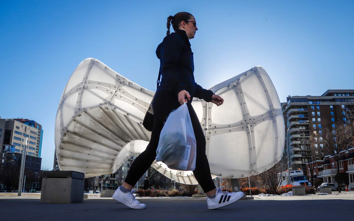 A woman walks past "Chinook Arc" in Calgary, Alta., Wednesday, Dec. 2, 2020.