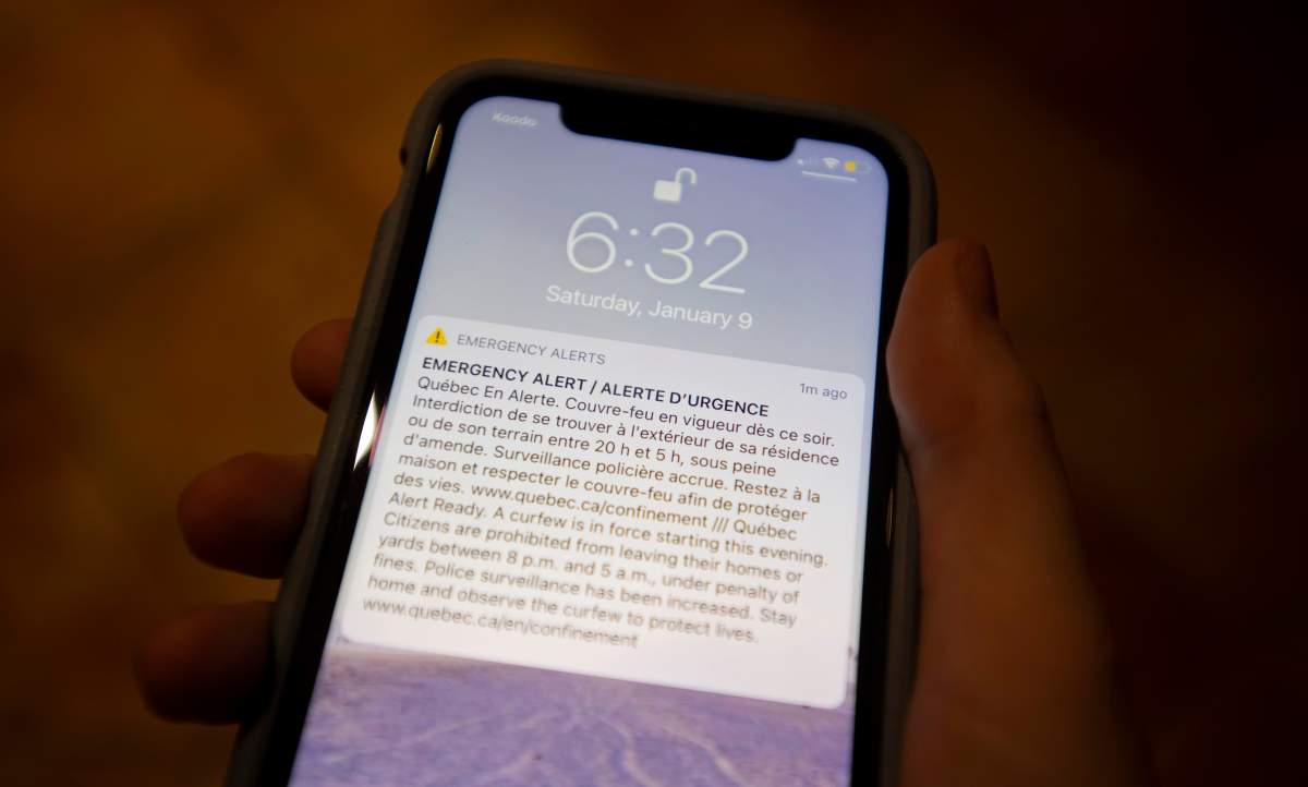 A woman holds her cell phone as an emergency broadcast reminds Quebec residents about the upcoming curfew on Saturday, January 9, 2021. 