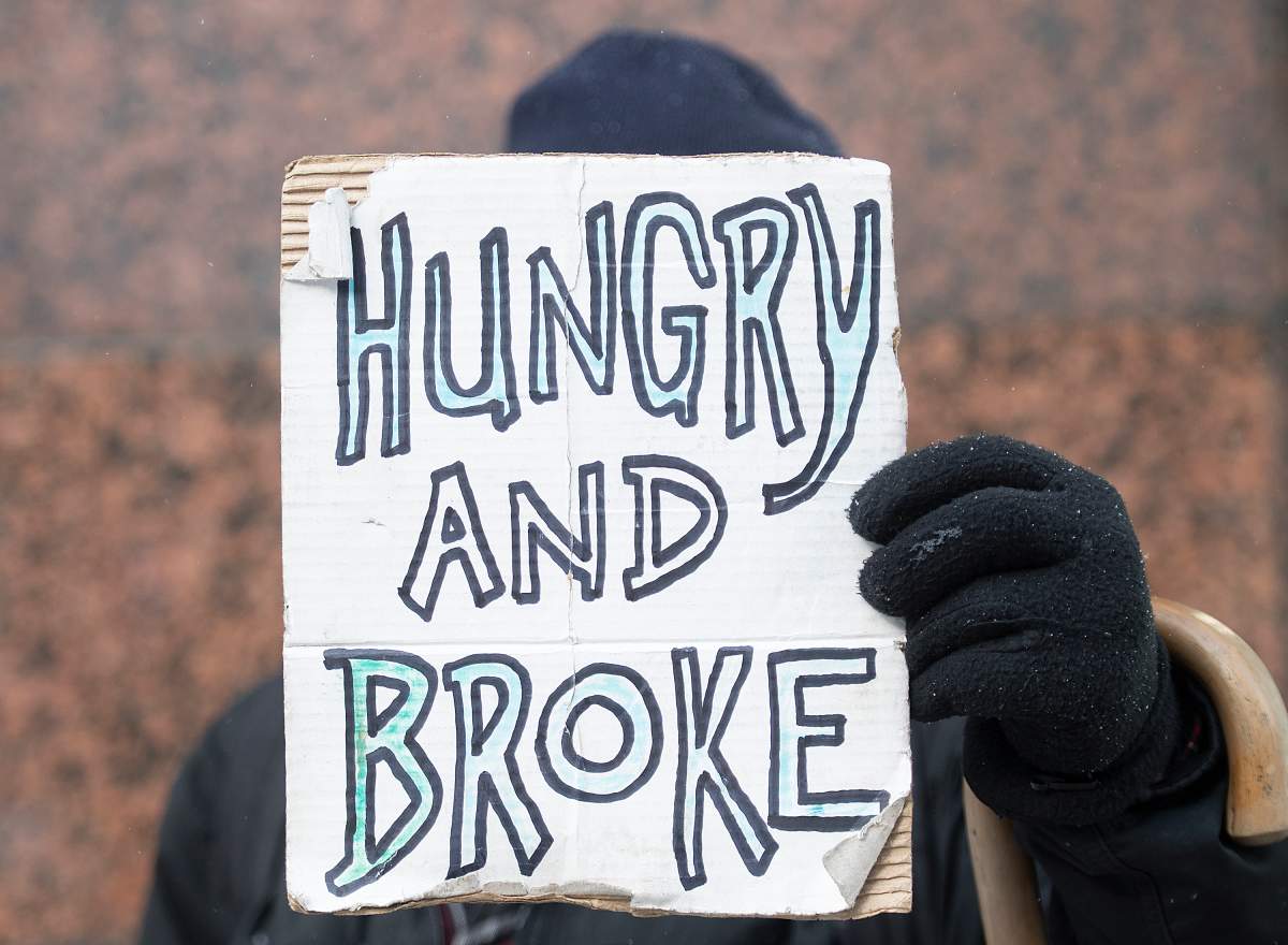 A homeless person holds up a sign in Montreal. A temporary shelter in Verdun that was slated to close July 31, will remain open for another month. FILE: Graham Hughes/The Canadian Press.