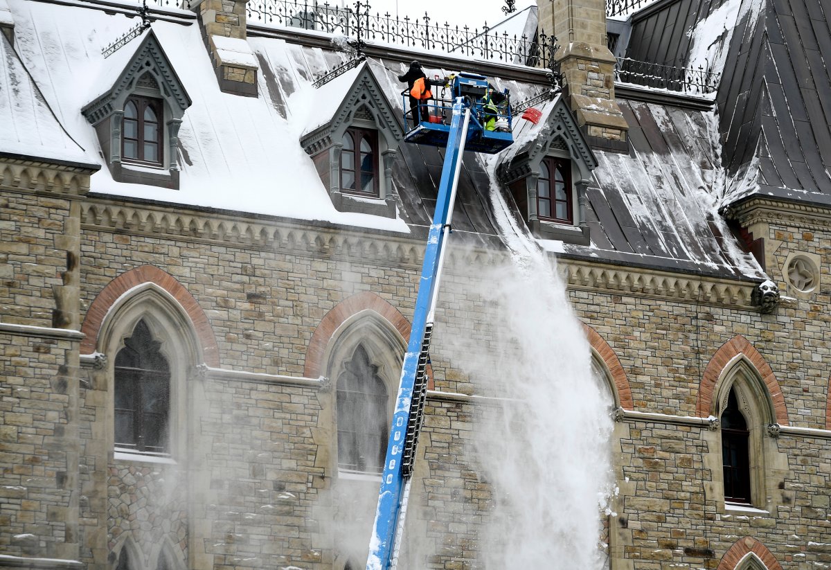 Workers on a boom lift use shovels to remove snow from the roof of Parliament Hill's West Block after an overnight snowfall in Ottawa earlier this winter. The region is due for another blast of snow on March 1, 2021.