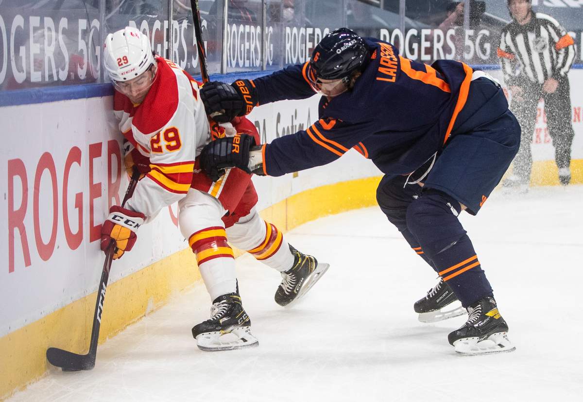 Edmonton Oilers' Adam Larsson (6) checks Calgary Flames' Dillon Dube (29) during first period NHL action in Edmonton on Saturday, February 20, 2021. THE CANADIAN PRESS/Jason Franson.