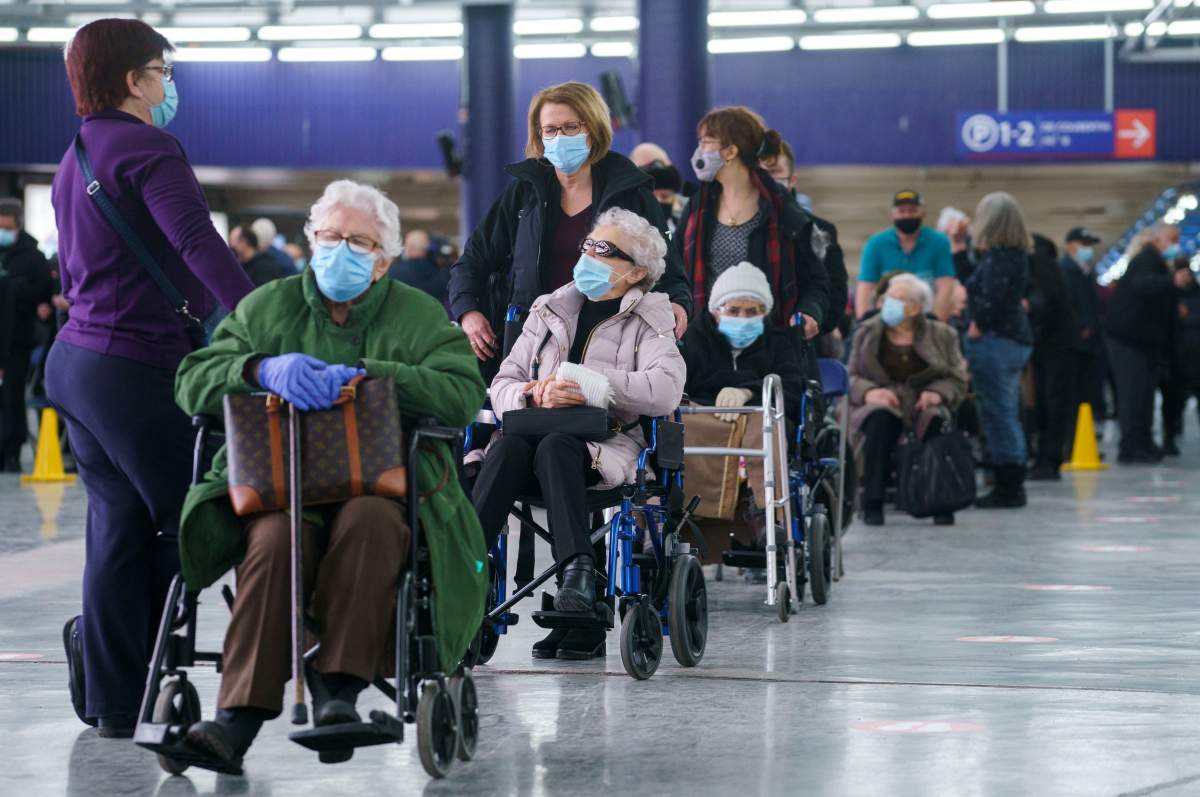 People wait in line at a COVID-19 vaccine at a clinic at Olympic Stadium marking the beginning of mass vaccination in the province of Quebec based on age in Montreal, on Monday, March 1, 2021. 
