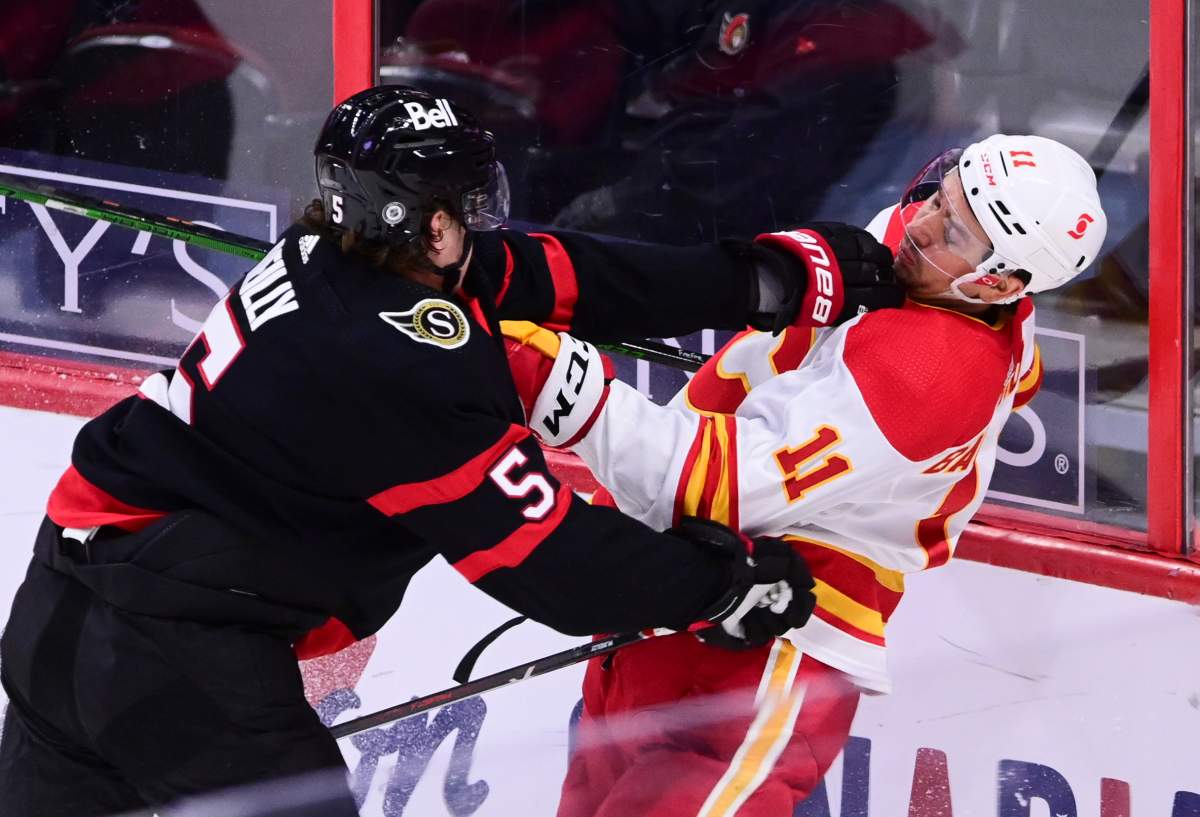 Ottawa Senators defenceman Mike Reilly (5) gives Calgary Flames centre Mikael Backlund (11) a shove during second period NHL action in Ottawa on Monday, March 1, 2021.
