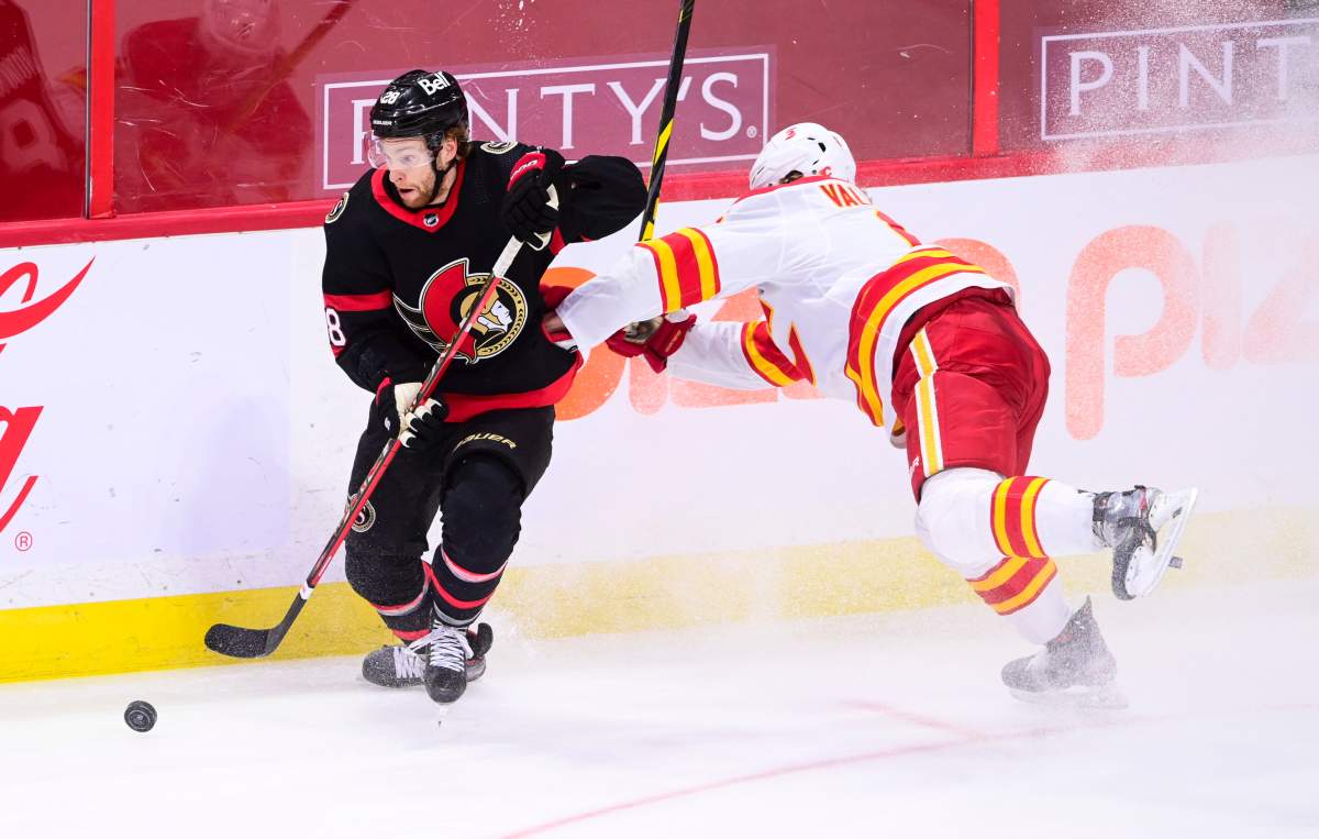 Ottawa Senators right wing Connor Brown (28) skates the puck away from Calgary Flames defenceman Juuso Valimaki (6) during third period NHL action in Ottawa on Monday, March 1, 2021.