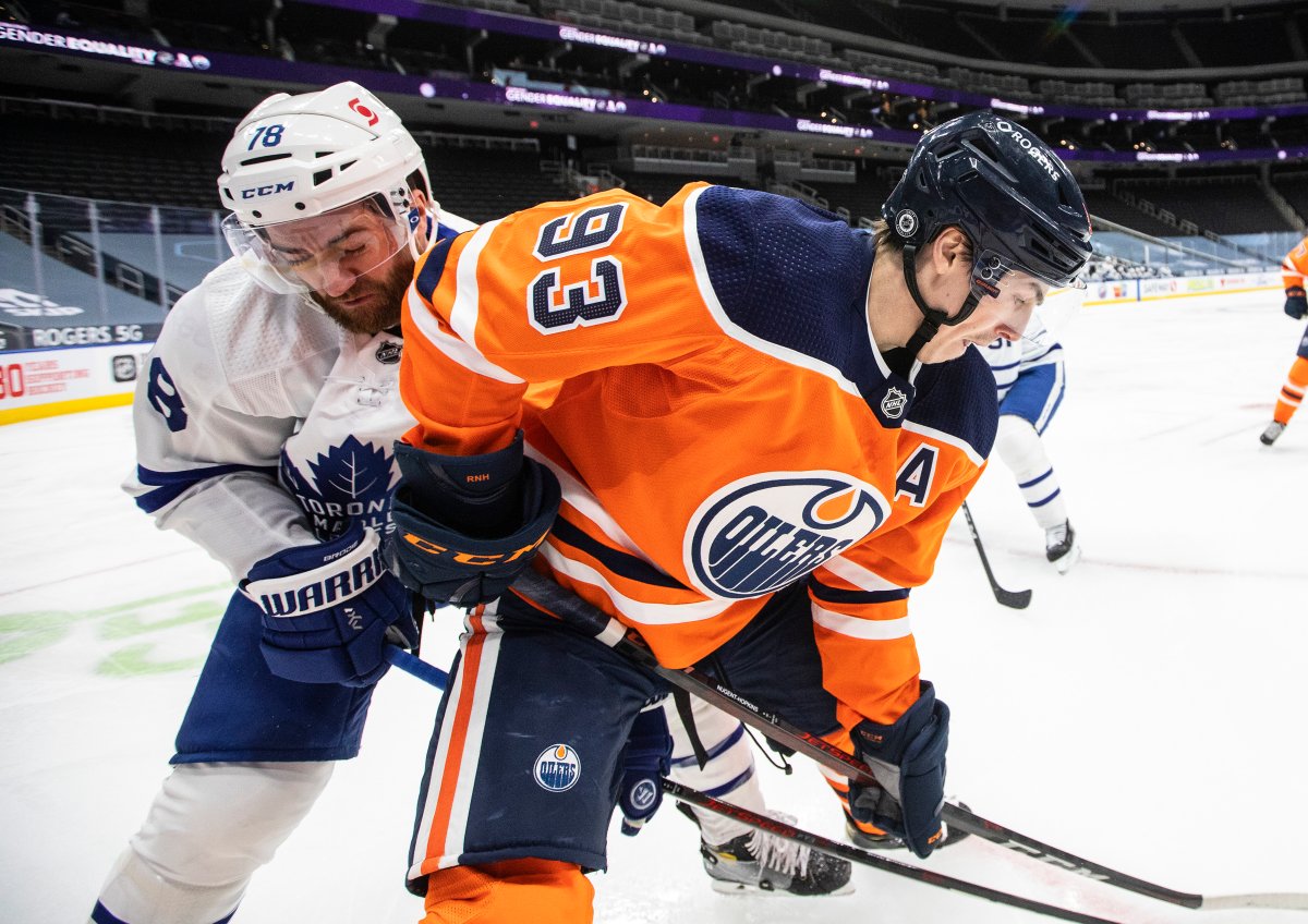 Edmonton Oilers' Ryan Nugent-Hopkins (93) and Toronto Maple Leafs' T.J. Brodie (78) battle for the puck during second period NHL action in Edmonton on Monday, March 1, 2021.THE CANADIAN PRESS/Jason Franson.