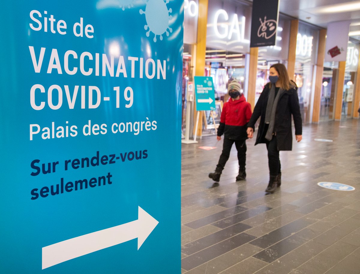 People walk past a COVID-19 vaccination clinic Thursday, March 4, 2021 in Montreal. 