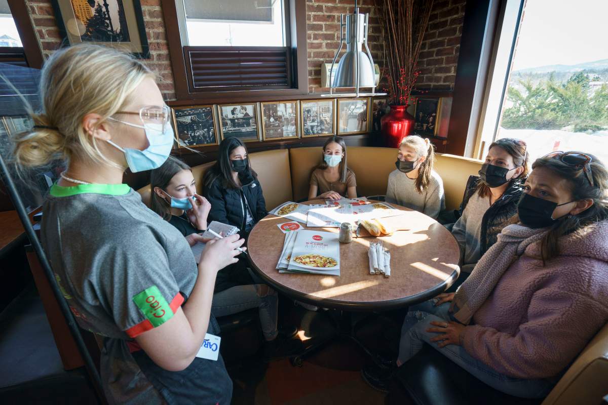 Waitress Myrtille Faucher takes customers' orders at the Eastside Mario's restaurant in Bromont, Que., on Monday, March 8, 2021. Customers are allowed to dine in as of Monday in restaurants outside of Greater Montreal. 