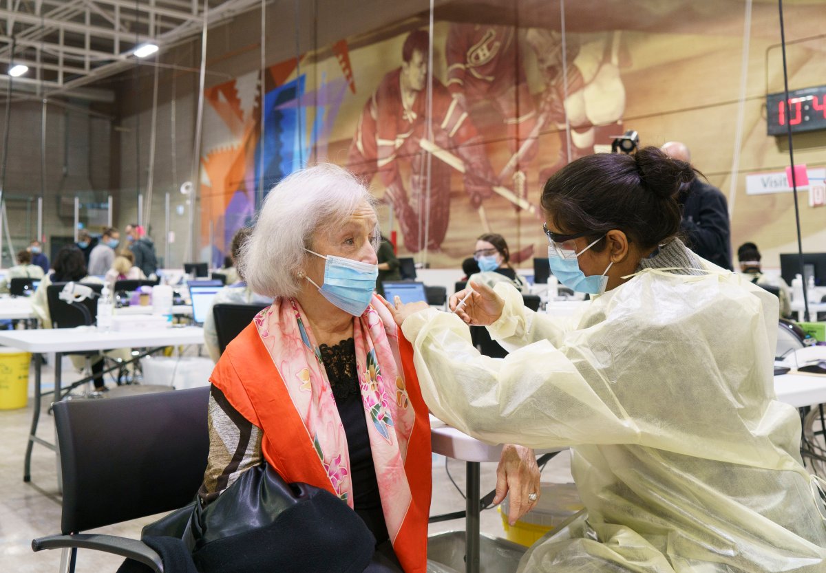 A senior citizen receives a first dose of COVID-19 vaccine at a vaccination clinic in a hockey arena in Montreal, on Wednesday, March 10, 2021. 
