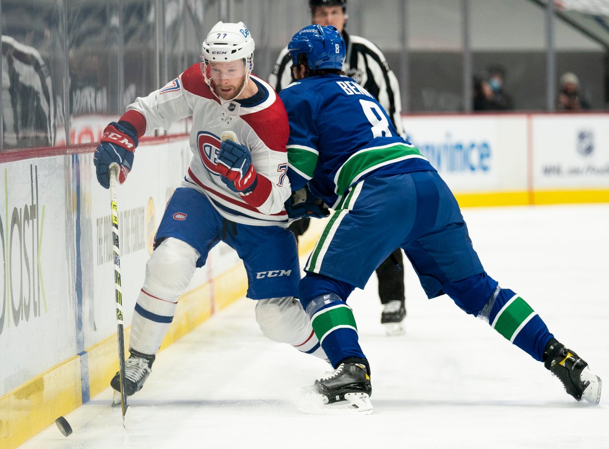 Montreal Canadiens defenceman Brett Kulak (77) is checked by Vancouver Canucks defenceman Jordie Benn (8) during first period NHL action in Vancouver on March 10, 2021.