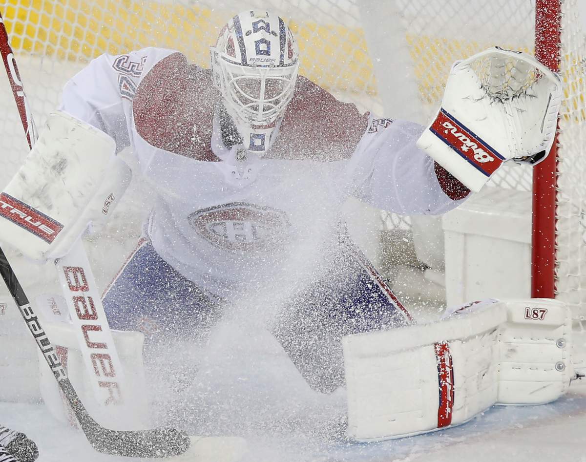 Montreal Canadiens goalie Jake Allen gets a face full of snow from Calgary Flames' Nikita Nesterov during the second period of their NHL hockey game in Calgary, Thursday, March 11, 2021.