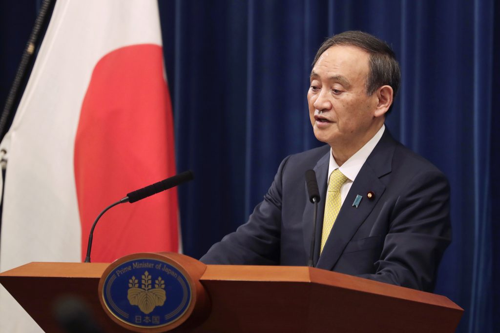 FILE - In this Dec. 4, 2020, file photo, Japanese Prime Minister Yoshihide Suga speaks during a news conference in Tokyo. Japan's government announced Friday, March 12, 2021 that Suga will travel to Washington next month for his first face-to-face summit with U.S. President Joe Biden after he and his entourage complete their COVID-19 vaccinations. (AP Photo/Hiro Komae, Pool, File).