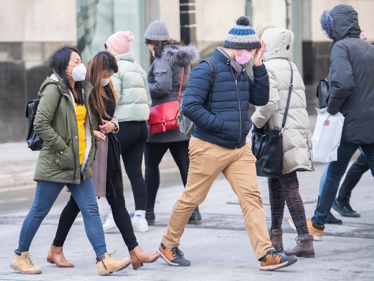 People wear face masks as they cross a street in Montreal, Saturday, March 13, 2021, as the COVID-19 pandemic continues in Canada and around the world. 