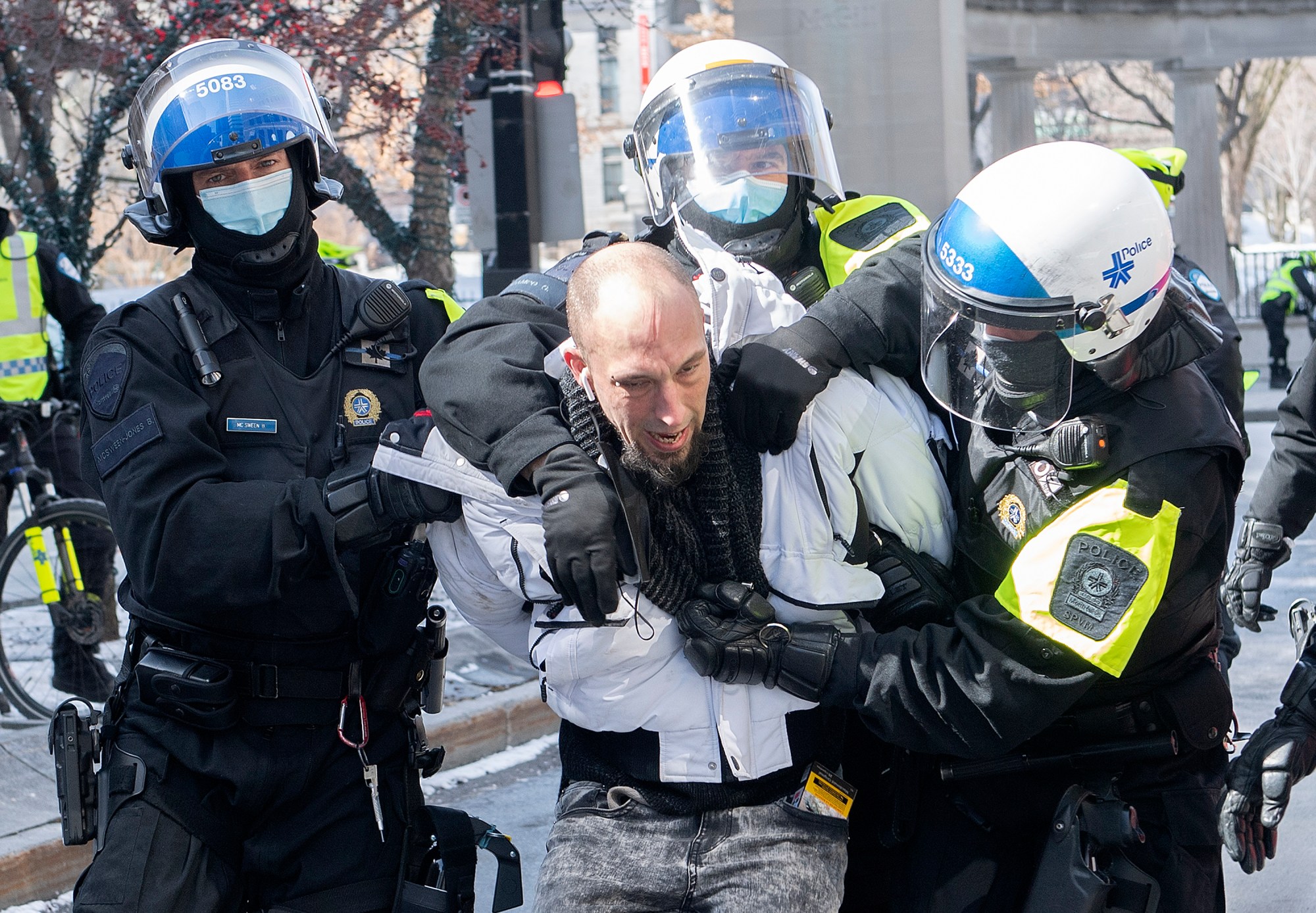 A man is detained by police during a demonstration to oppose government restrictions to curb the spread of Covid-19 in Montreal, Saturday, March 13, 2021.
