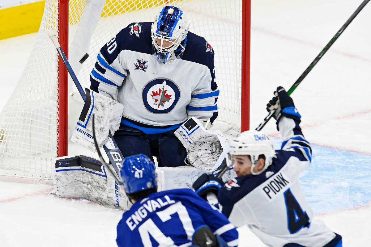 Toronto Maple Leafs left wing Pierre Engvall (47) scores what would be determined to be a disallowed goal on Winnipeg Jets goaltender Laurent Brossoit (30) as Winnipeg Jets defenceman Neal Pionk (4) defends during first-period NHL action in Toronto on Saturday, March 13, 2021.