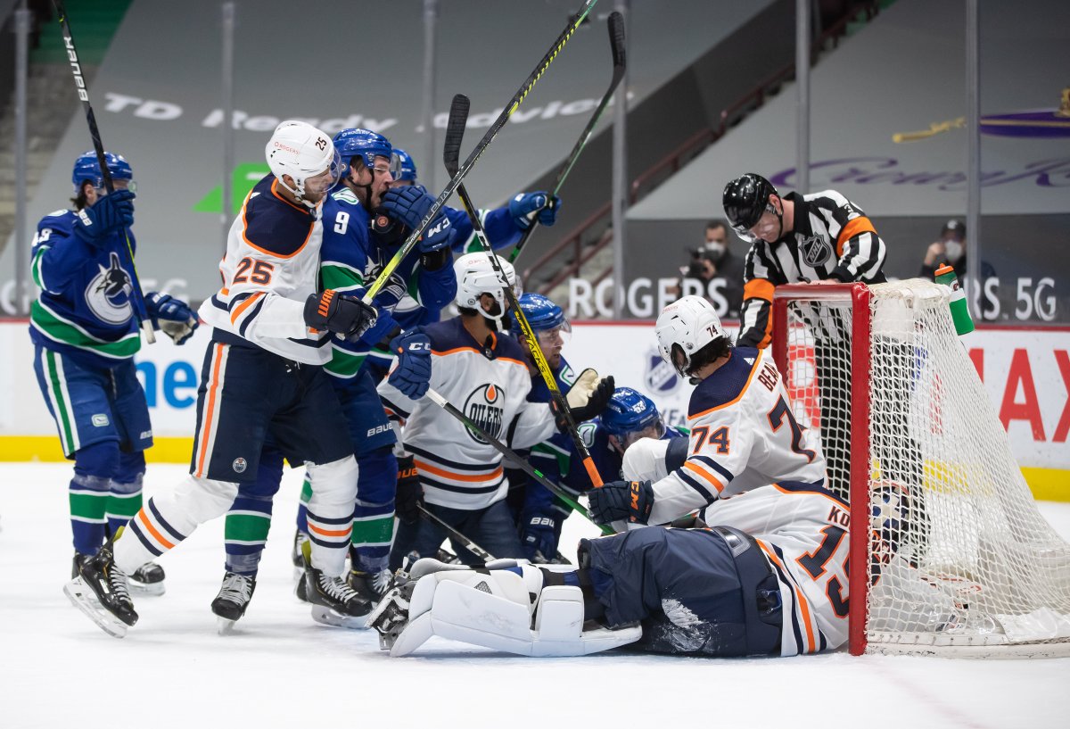 Edmonton Oilers' Darnell Nurse (25) grabs Vancouver Canucks' J.T. Miller (9) after Bo Horvat (53) scored against Edmonton goalie Mikko Koskinen (19), of Finland, during the second period of an NHL hockey game in Vancouver, on Saturday, March 13, 2021. THE CANADIAN PRESS/Darryl Dyck.