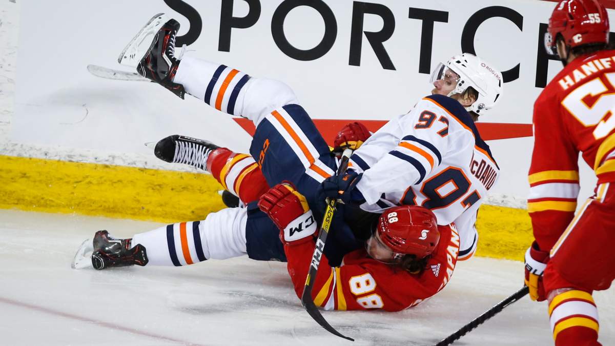 Edmonton Oilers’ Connor McDavid, right, crashes down on Calgary Flames’ Andrew Mangiapane during third-period NHL hockey action in Calgary on Monday, March 15, 2021.