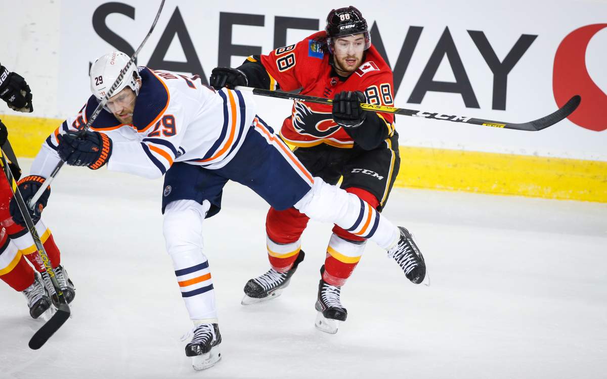 Edmonton Oilers’ Leon Draisaitl, left, is checked by Calgary Flames’ Andrew Mangiapane during second period NHL hockey action in Calgary, Wednesday, March 17, 2021.