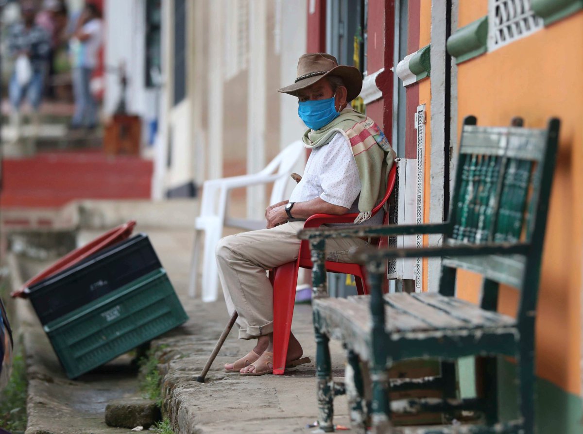 Wearing a mask to curb the spread of the new coronavirus, a man sits on his front porch in Campohermoso, Colombia, Thursday, March 18, 2021. According to the Health Ministry, Campohermoso is one of two municipalities in Colombia that has not had a single case of COVID-19 since the pandemic started one year ago.