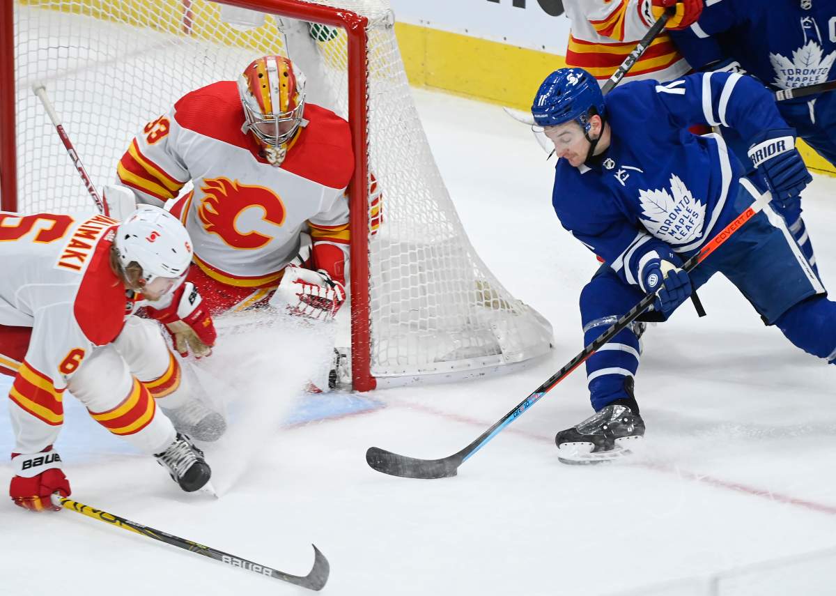 Toronto Maple Leafs forward Zach Hyman (11) shoots on Calgary Flames goaltender David Rittich (33) as Flames defenceman Juuso Valimaki (6) keeps close during second period NHL hockey action in Toronto on Saturday, March 20, 2021.