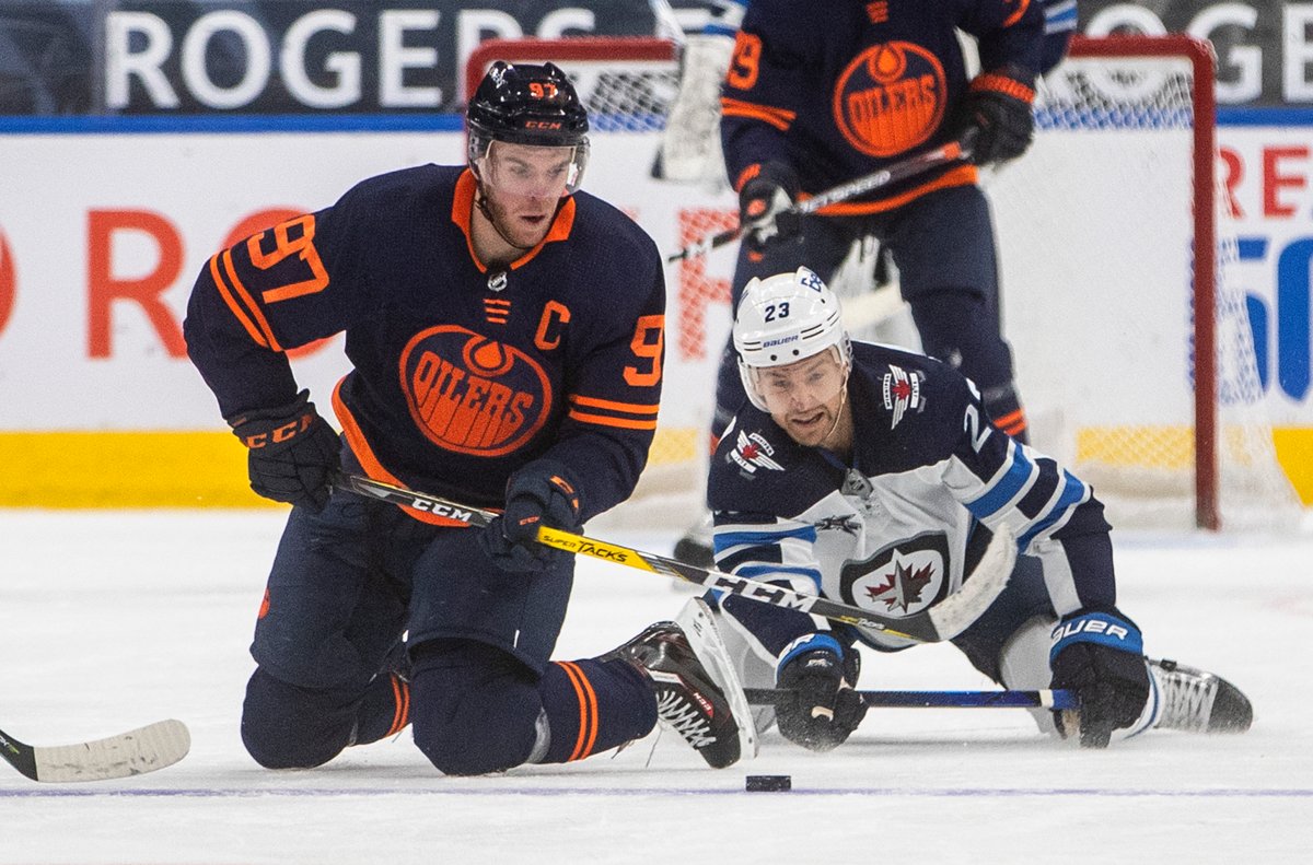 Connor McDavid of the Edmonton Oilers makes a play on the puck as the Winnipeg Jets' Trevor Lewis watches on during their game on Saturday, Mar. 21. 