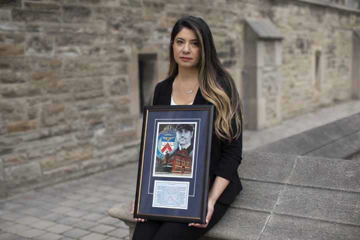Dilnaz Garda poses for a portrait holding a commemorative photo of her brother Darius, in Toronto, Thursday, March 18, 2021. Garda's brother Darius, a Toronto police officer, died by suicide, and Garda is part of the charity "Toronto beyond the blue" who are lobbying the Ontario Government for a proposed memorial on Queen’s Park grounds for police officers who have died by suicide.