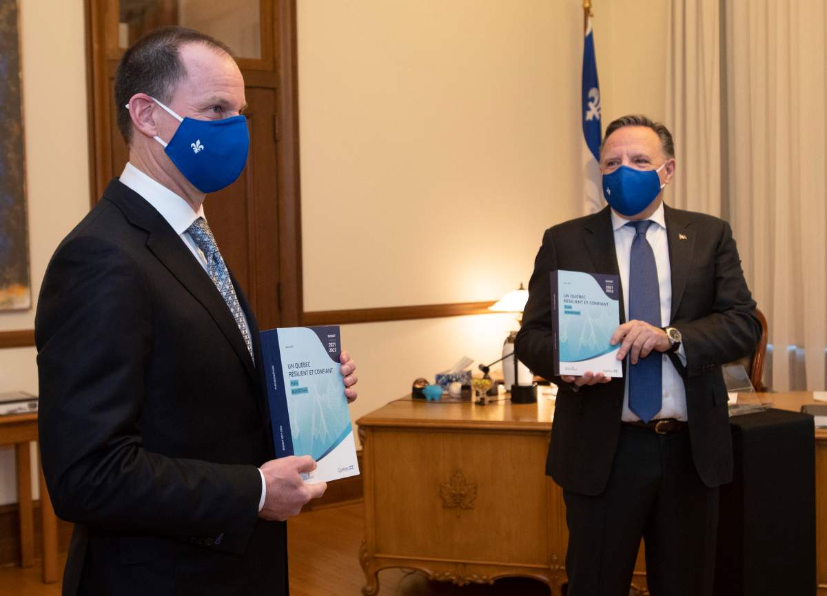 Quebec Finance Minister Eric Girard and Quebec Premier Francois Legault, right, each hold a copy of the budget speech, Thursday, March 25, 2021 at the Premier's office in Quebec City. 