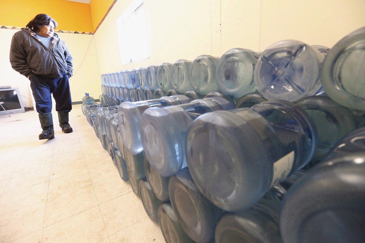 Stewart Redsky, former chief and current Alcohol/Drug Counsellor of Shoal Lake 40 First Nation, walks past one week's worth of 20 litre water bottles in the community's water storage room on February 25, 2015. A new study by Ontario researchers suggest recent technological advances in water monitoring could reduce significantly the number of drinking-water advisories on First Nations across the country. Edward McBean, an engineering professor at the University of Guelph and his former student, Kerry Black, explored the potential benefit for using real-time water monitoring systems on reserves throughout the country. THE CANADIAN PRESS/John Woods.