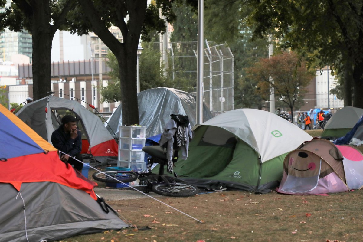 Tents set up by the homeless are seen in Moss Park in downtown Toronto on Wednesday, Sept. 23, 2020, as activists march in a nearby street. Several groups are suing the city for failing to protect the health and safety of homeless people during the COVID-19 pandemic.