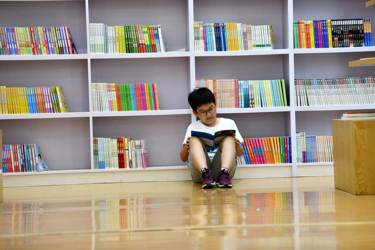 child reading book against book shelf
