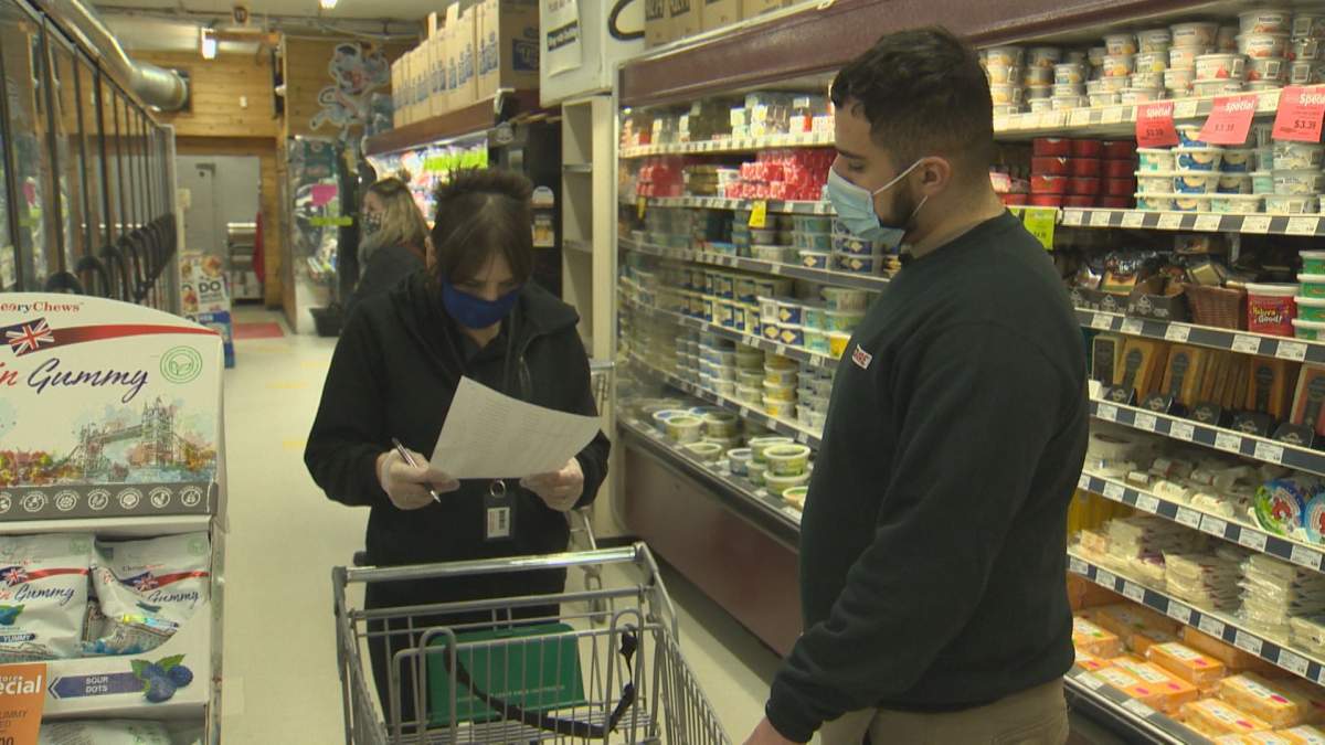 Tarik Zeid reviews a list of delivery orders with a co-worker at Food Fare in Winnipeg.