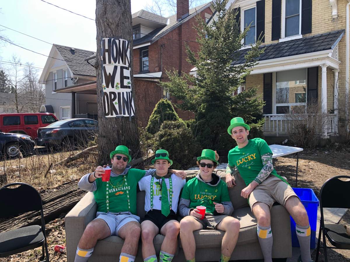 Ben Van Walleghem (second from left) sits on a couch with his housemates as they spend St. Patrick’s Day on their front lawn.