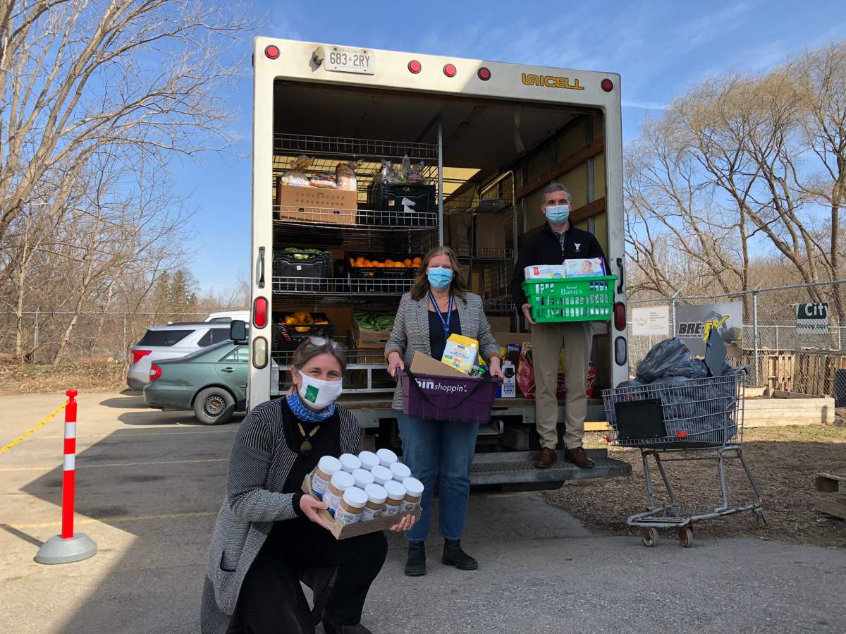 London Food Bank co-director Jane Roy (left),  South London Neighbourhood Resource Centre and Northwest London Resource Centre executive director Nancy Needham (centre), and YMCA of Southwestern Ontario CEO Andrew Lockie stand in at the back of a loaded Food Bank truck.