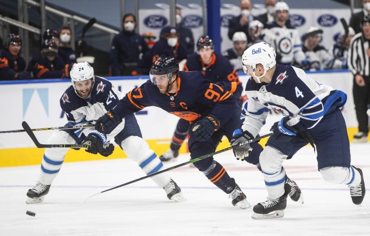 Edmonton Oilers’ Connor McDavid (97) is chased by Winnipeg Jets’ Derek Forbort (24) and Neal Pionk (4) during second period NHL action in Edmonton on Thursday, March 18, 2021.