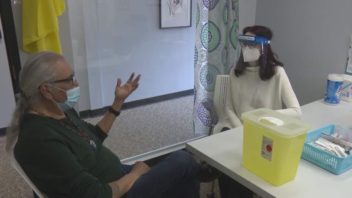 Beth Woytas and Earnie Poundmaker chat inside a COVID-19 vaccination clinic for Indigenous people living in and around Calgary.