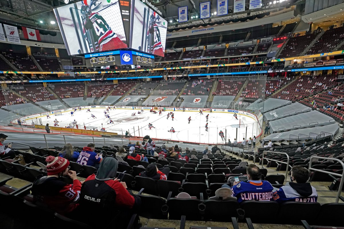 Fans sit in the stands watching teams warm up before an NHL hockey game between the New Jersey Devils and the New York Islanders, Tuesday, March 2, 2021, in Newark, N.J. It was the first time fans were allowed in the Prudential Center under New Jersey's new COVID-19 rules.