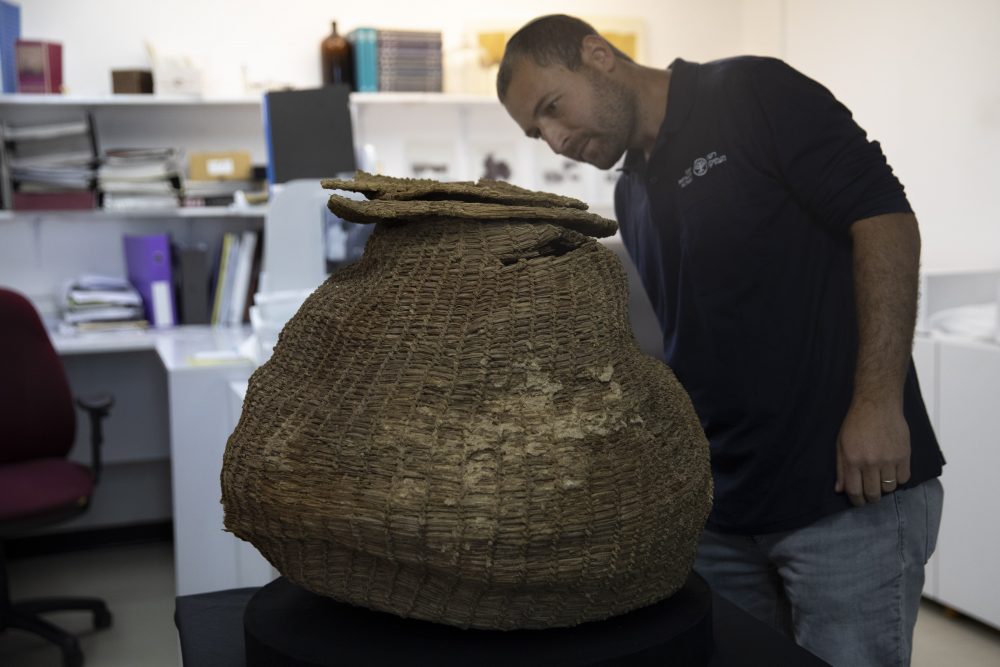Archeologist Haim Cohen looks at a woven basket that was found during a sweep of more than 500 caves in the desert, at the Israeli Antiquities Authority Dead Sea scrolls conservation lab in Jerusalem, Tuesday, March 16, 2021.