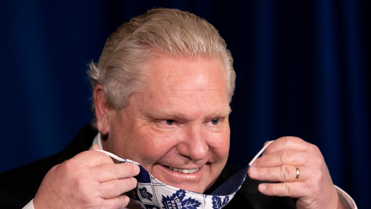 Ontario Premier Doug Ford puts on his Toronto Maple Leafs mask during the daily briefing in Toronto in February 2021. 