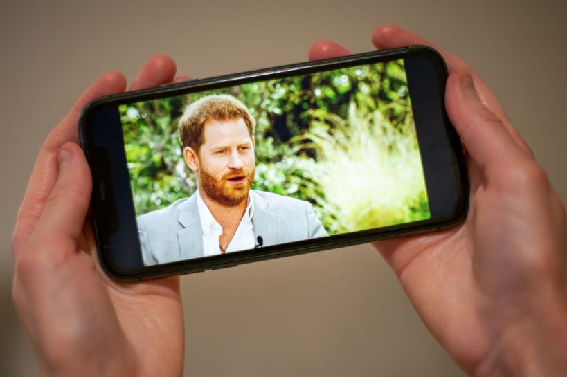 A man watches the Duke and Duchess of Sussex interview with Oprah Winfrey, which is being shown on ITV, on a phone screen in a flat in London. 