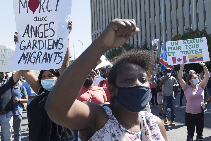 IN this file photo, people take part in a protest outside Prime Minister Justin Trudeau's constituency office in Montreal, Saturday, August 15, 2020, where they called on the government to give permanent residency status to all migrant workers and asylum seekers.