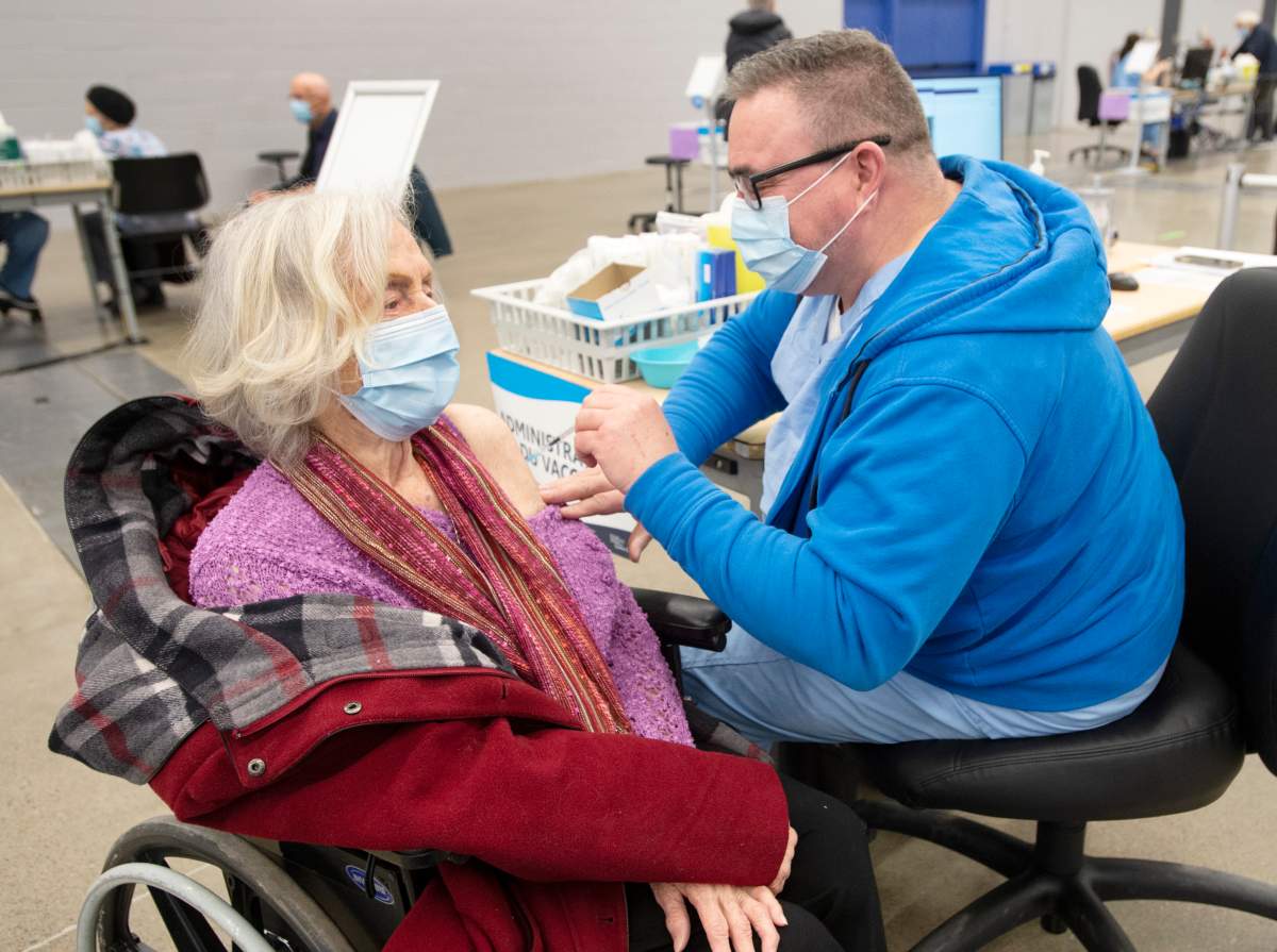 A senior receives her COVID-19 vaccination at the Palais de Congress site as Quebec begins mass vaccinations based on age across the province, Monday, March 1, 2021.