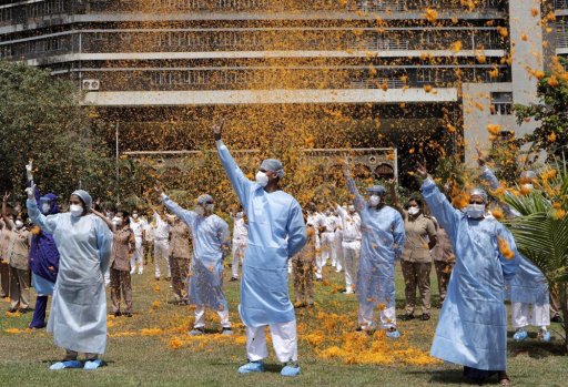 In this May 3, 2020, file photo, an Indian Air Force helicopter showers flower petals on the staff of INS Asvini hospital in Mumbai, India. The event was part the Armed Forces’ efforts to thank the workers, including doctors, nurses and police personnel, who have been at the forefront of the country’s battle against the COVID-19 pandemic.