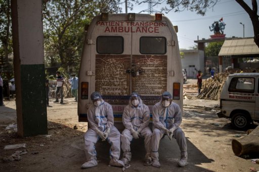 Exhausted workers, who bring dead bodies for cremation, sit on the rear step of an ambulance inside a crematorium, in New Delhi, India, Saturday, April 24, 2021. As India suffers a bigger, more infectious second wave with a caseload of more than 300,000 new cases a day, the country’s healthcare workers are bearing the brunt of the disaster.