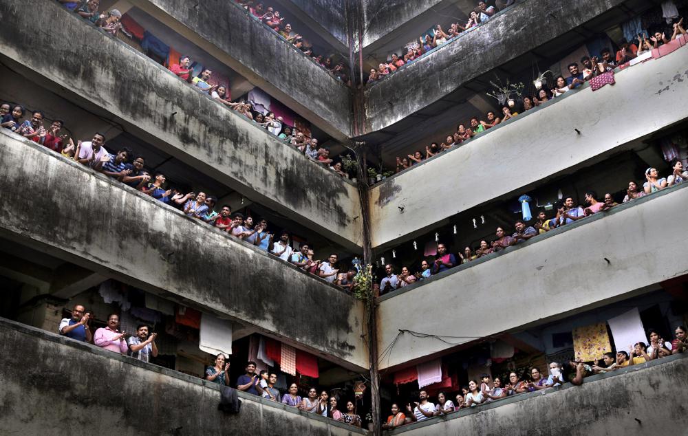 In this March 22, 2020, file photo, people clap from balconies in show of appreciation to health care workers as they observe a 14-hour “people’s curfew” called by Prime Minister Narendra Modi in order to stem the rising coronavirus caseload in Mumbai, India.