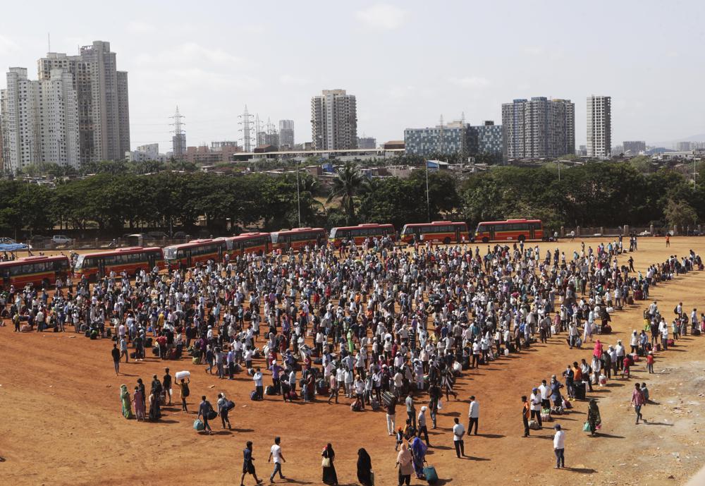 In this May 20, 2020, file photo, migrant workers from other states line up to board buses for their onward journey by train to their destination in Mumbai, India.